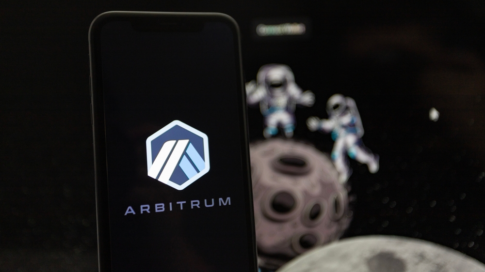 A man holds an iPhone XR where the logo of the Ethereum layer 2 platform Arbitrum can be seen