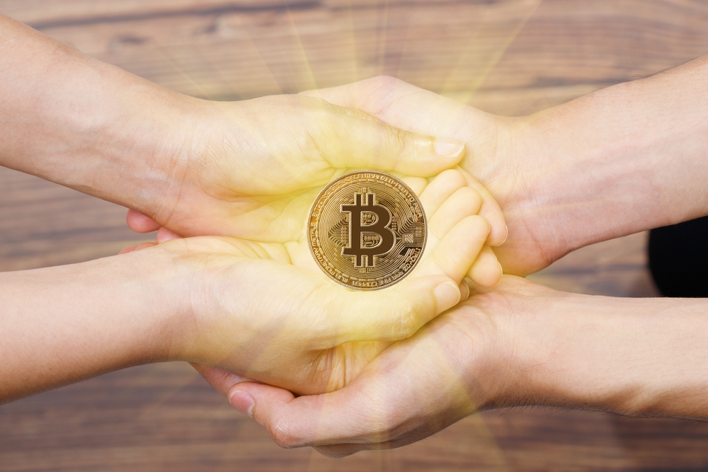 People Hands together give and receive love of BTC Bitcoin on empty palm hands. Future of Crypto Currency will Heritage Gift to Family. Concept Love share with technology over wooden background