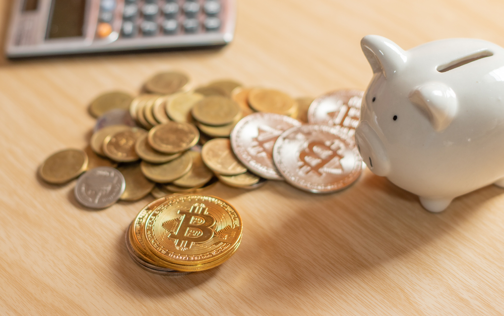 Selective focus gold digital crypto currency coin set background on wooden table with piggy bank and calculator Ideas for planning savings for future retirement.