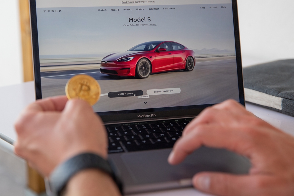 A man considers buying a tesla by paying with Bitcoins. Tesla allows you to buy products with cryptocurrencies.