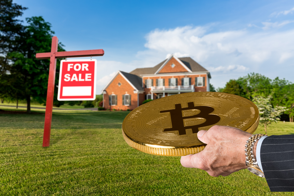Businessman or finance executive in suit offering bitcoin to purchase large single family home