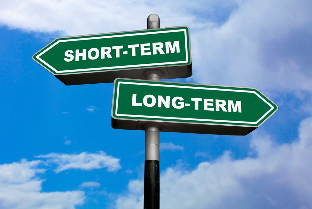 Long term vs Short term concept. Two street signs with arrow on metal pole on blue sky background. Business investment concept. 