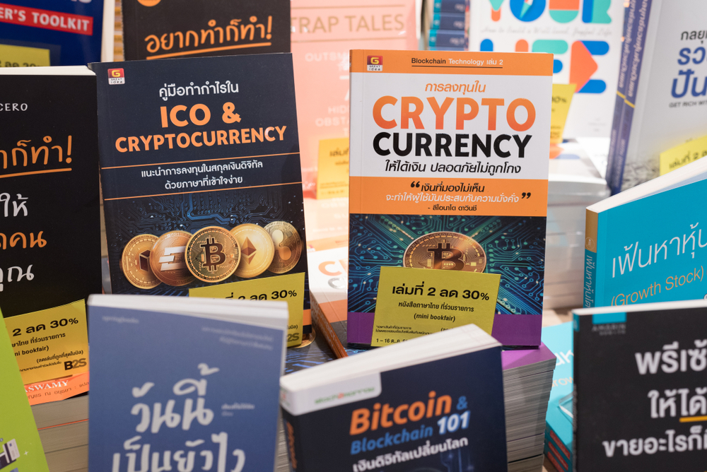 books on crypto currency, bitcoin and blockchain technology in Thai language on a shop shelf of a bookstore.