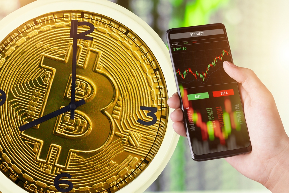 The Bitcoin Clock represents the time of trading cryptocurrency. and trader investor analyst using mobile phone app analytics for cryptocurrency financial