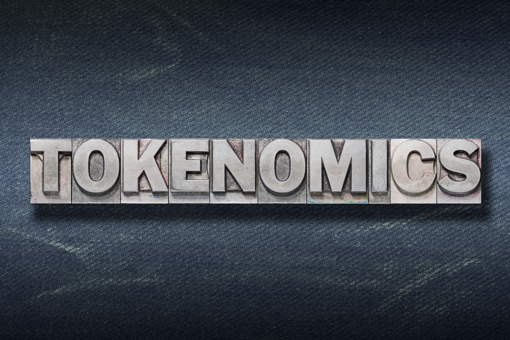 tokenomics word made from metallic letterpress on dark jeans background