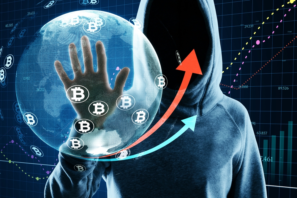 Hacker in hoodie using glowing globe hologram with financial arrows and money signs on blurry background.