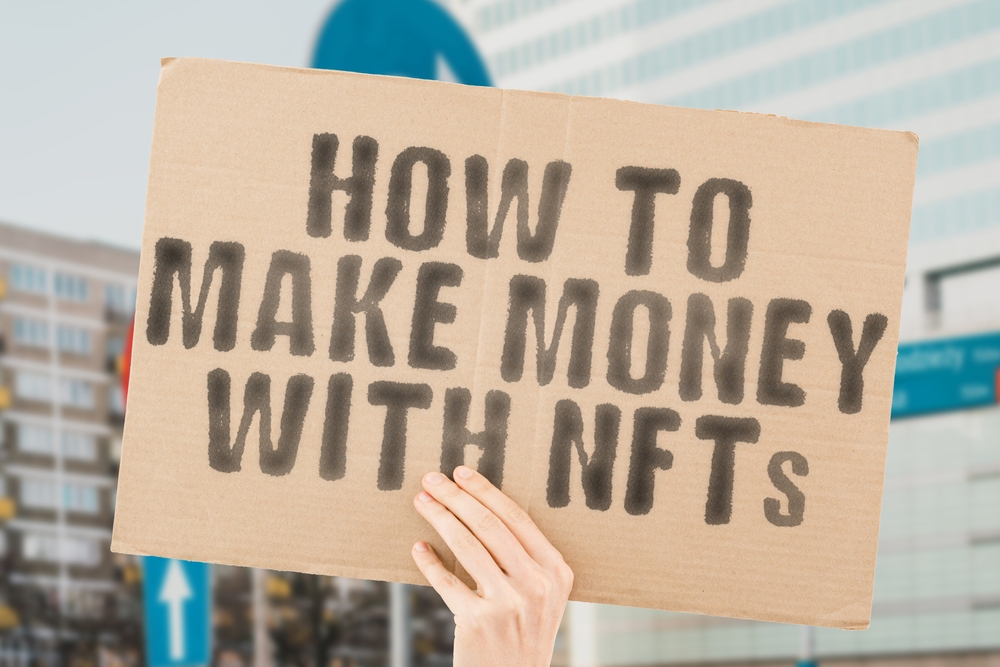 The phrase " How to make money with NFTs " is on a banner in men's hands with blurred background. 