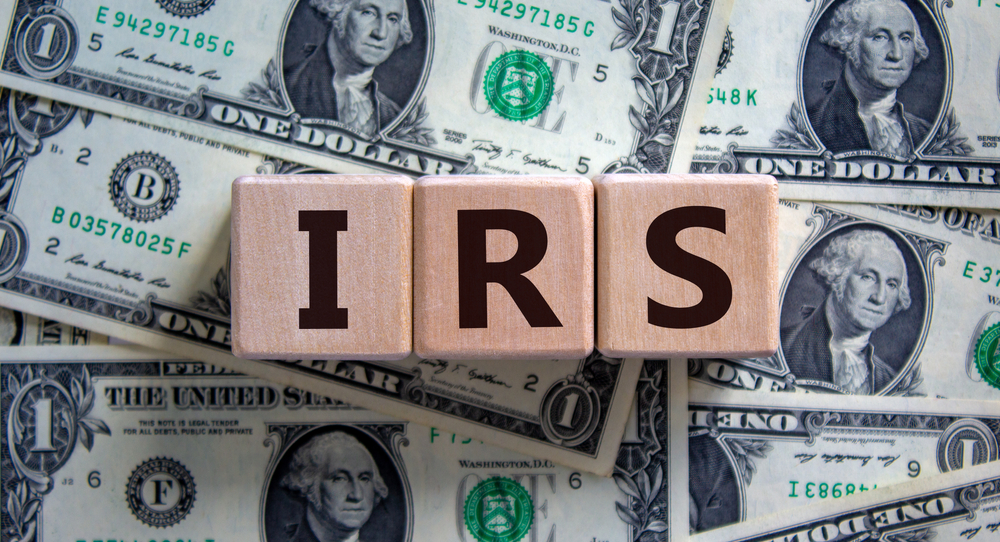 Concept word 'IRS - Internal Revenue Service' on wooden blocks on a beautiful background from dollar bills.