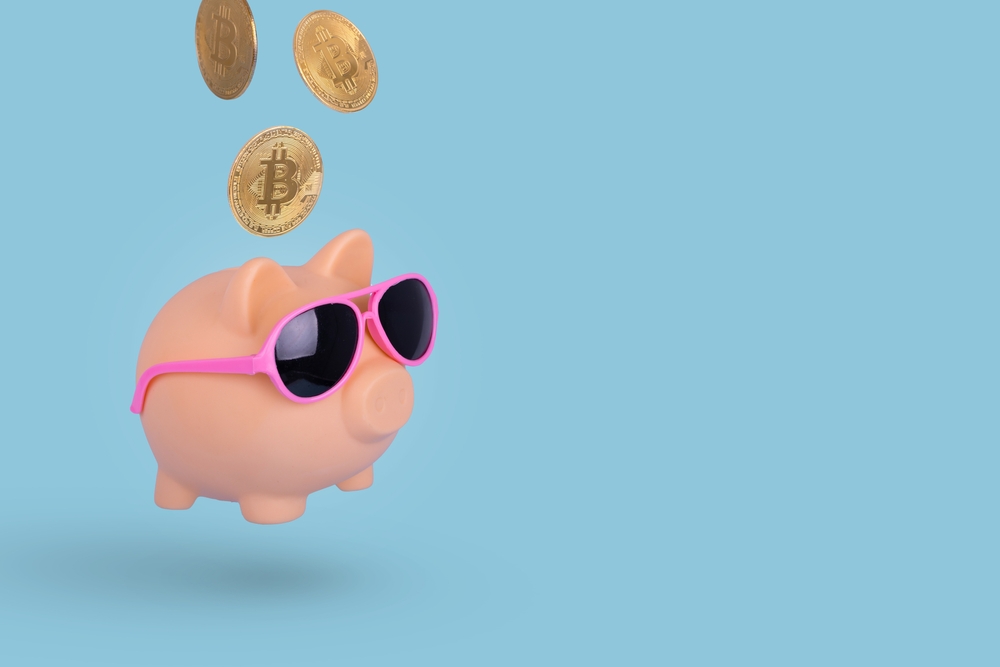 Creative idea with golden Bitcoins and Piggy Bank wearing sunglasses isolated on a bright blue background.