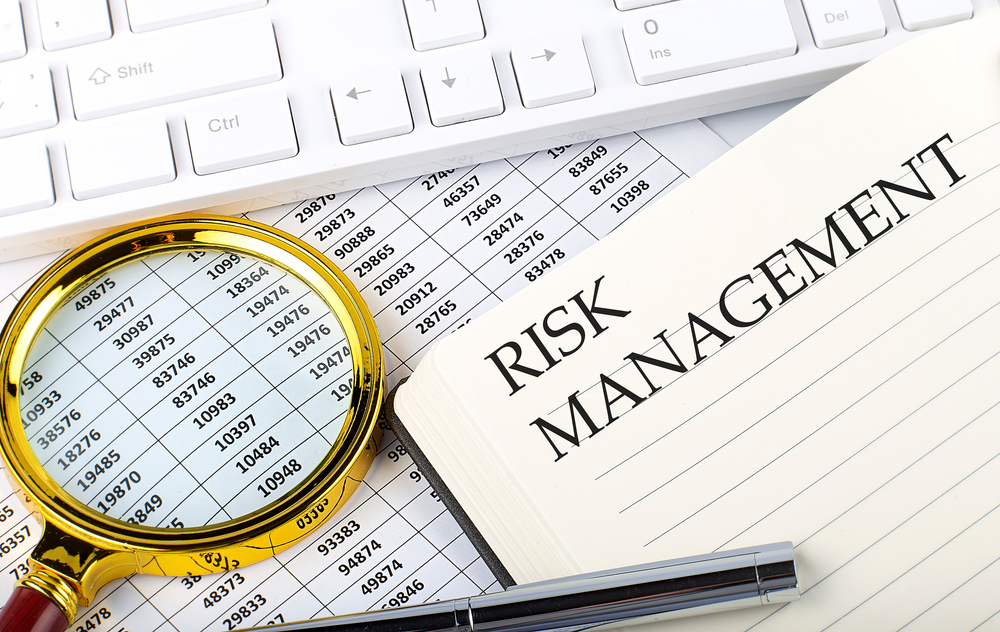 RISK MANAGEMENT text on notebook with chart, magnifier,keyboard and pen