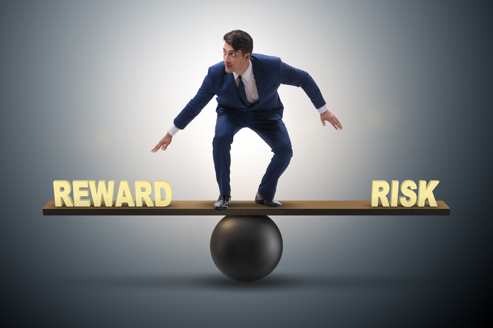 Businessman balancing between reward and risk business concept