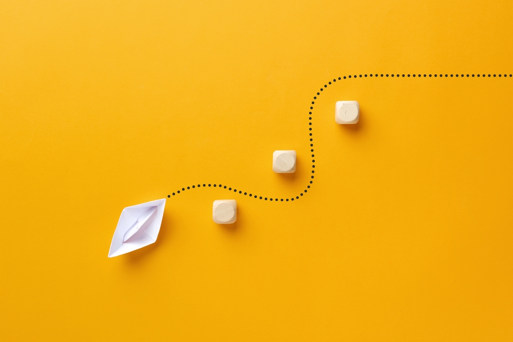 Origami paper boat passes through the wooden cube barriers.