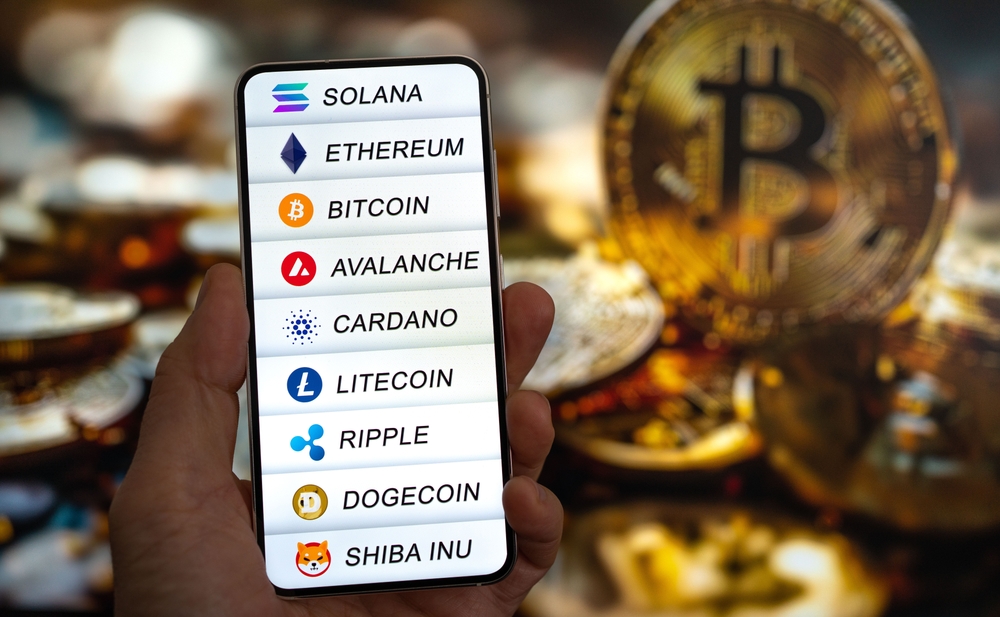 Hand holding mobile with CoinMarketCap app running at smartphone screen with list of today's cryptocurrency prices, trading candlestick chart in background