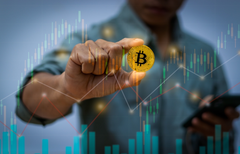 Close-up of a business man's hand holding a gold coin of digital currency. Overlaid with statistical candlestick charts. Data Analysis Ideas for Investing and Investor Strategies. 