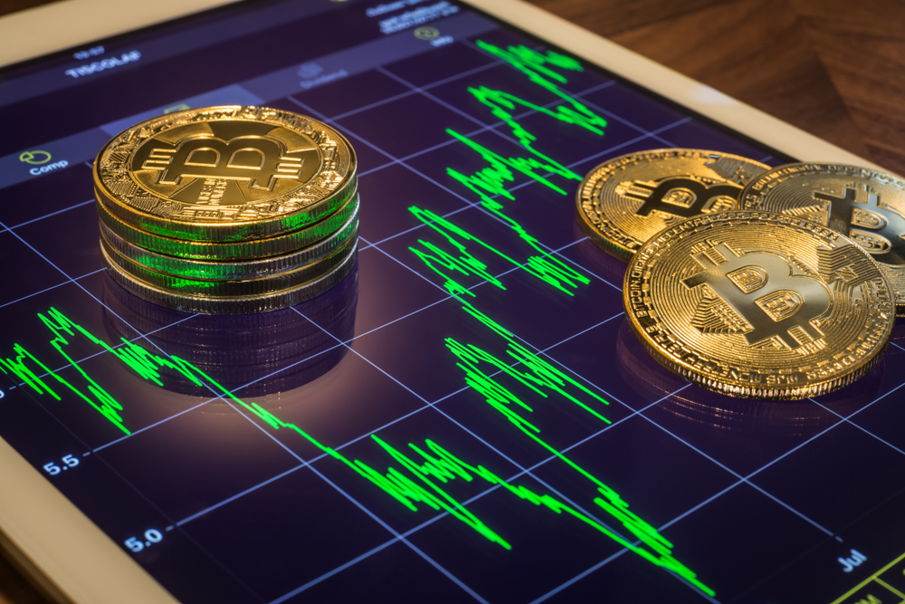 Cryptocurrency concepts, focus Bitcoin on tablet screen that showing green price or stock market performance graph, light reflect. Decentralized, transfer or exchange digital money through blockchain.