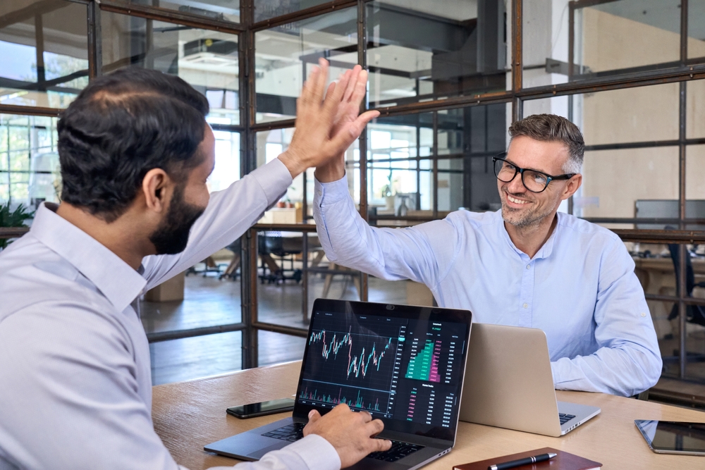 Two happy successful excited diverse traders investors giving high five celebrating successful stock exchange trading deal