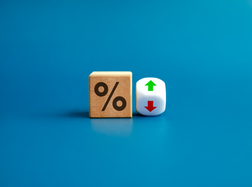 Percentage icon on wooden cube block and up and down arrow symbol on flipping white dice on blue background. Interest rate, financial stocks, ranking, GDP percent change, money exchange concepts.