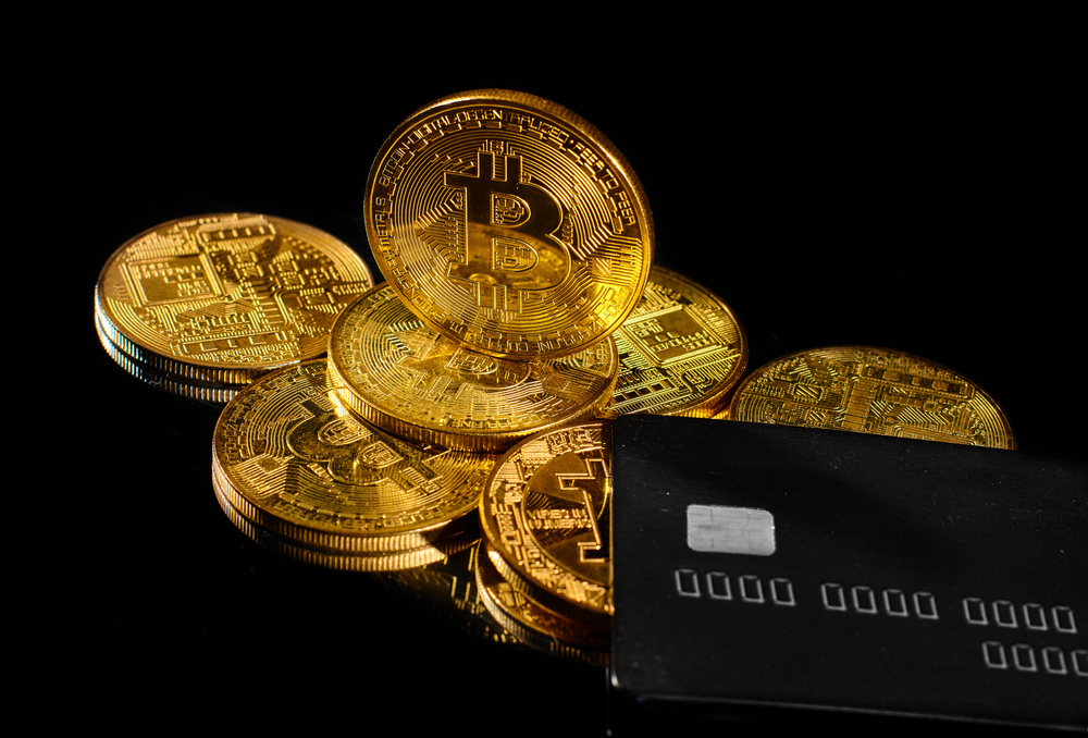 Golden coin with bitcoin logo and credit card. Leader in cryptocurrency BTC and bitcoin rewards card against black surface. Decentralized digital currency. Crypto payment. Electronic money or e-cash