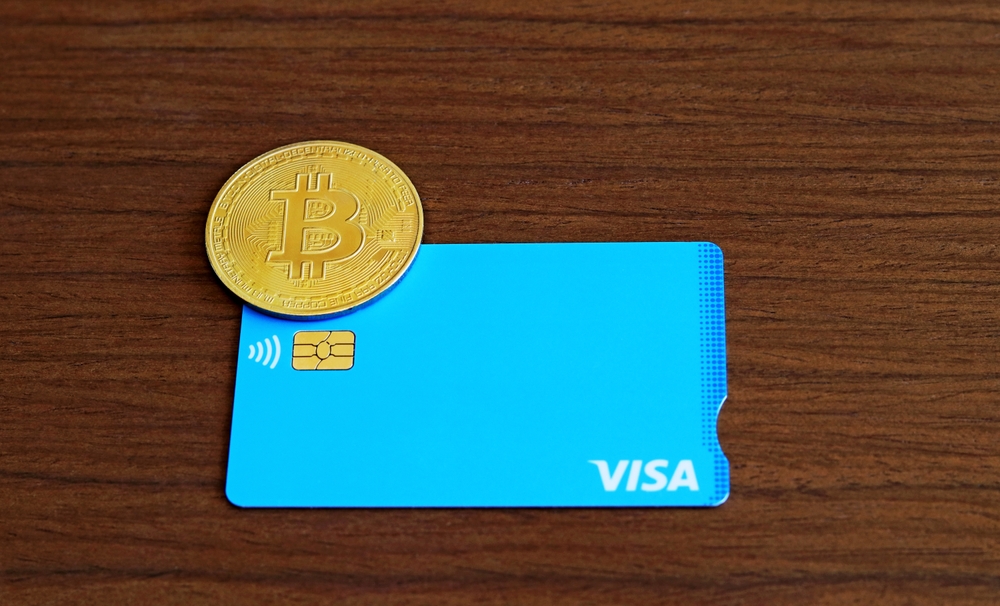 A credit or debit card next to a bitcoin coin