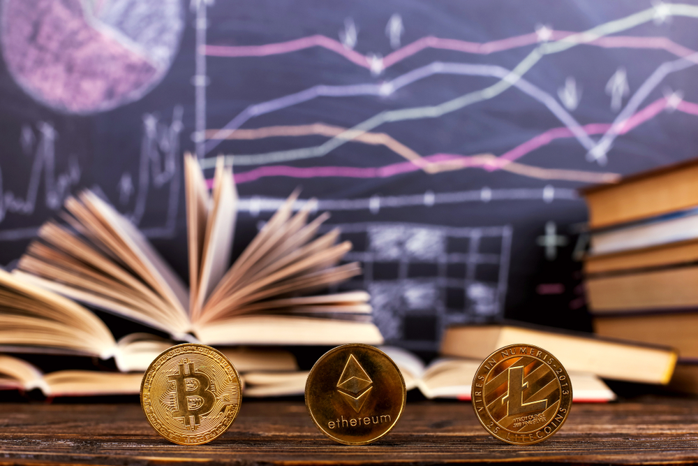 Books on the table against the background of chalkboard are drawn charts and patterns of growth and decline of crypto.