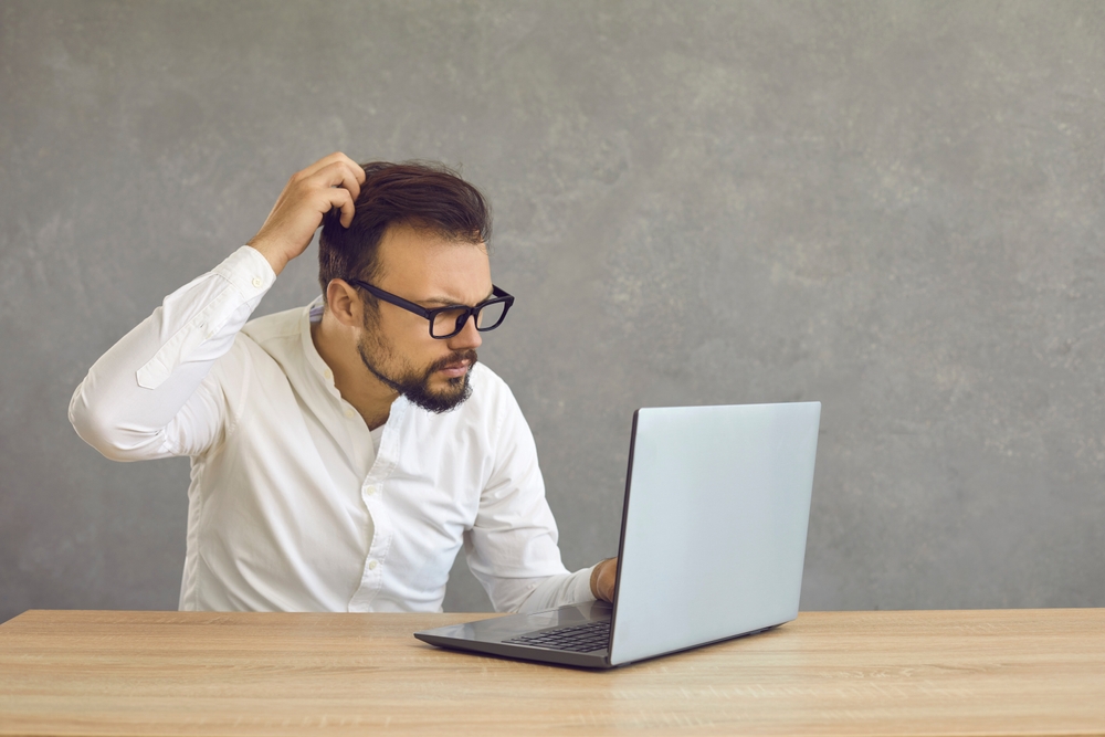 Portrait of confused man looking at computer screen. 