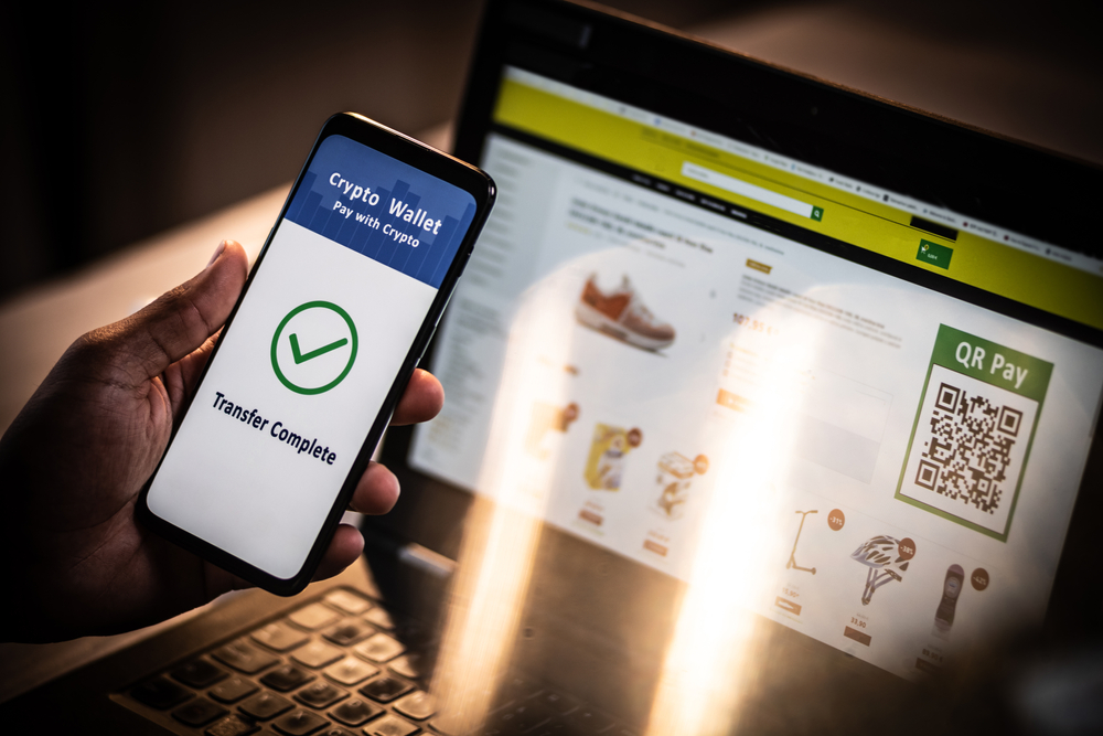 Close up of an African American male hand holding mobile phone with QR pay application on the screen, laptop in the background