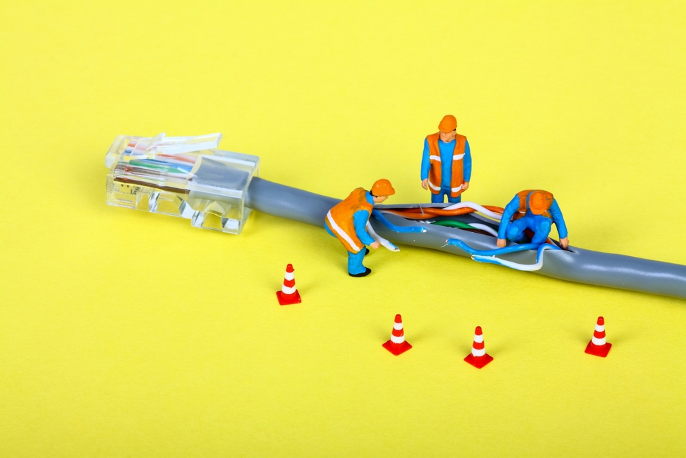 Conceptual image of miniature figure workmen investigating a fault on a broadband network cable