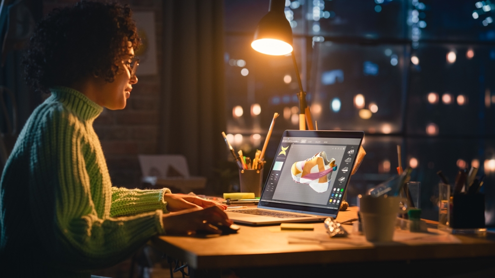 Latina Female Designer Working on Laptop, Screen Showing Editing Software with 3D Model of a Shoe.