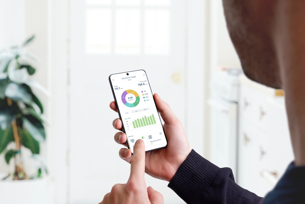 Guy monitors home electricity usage with smart home app.