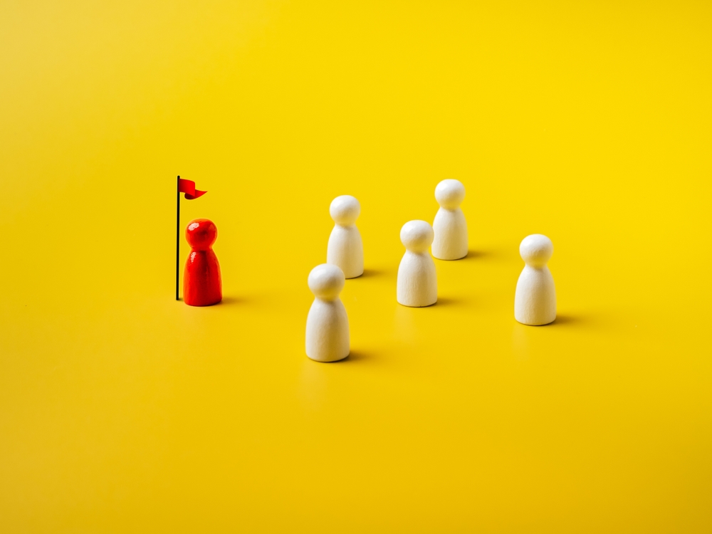 The leader red different one stay with flag, leading white peg dolls group, team symbol, isolated on yellow background.